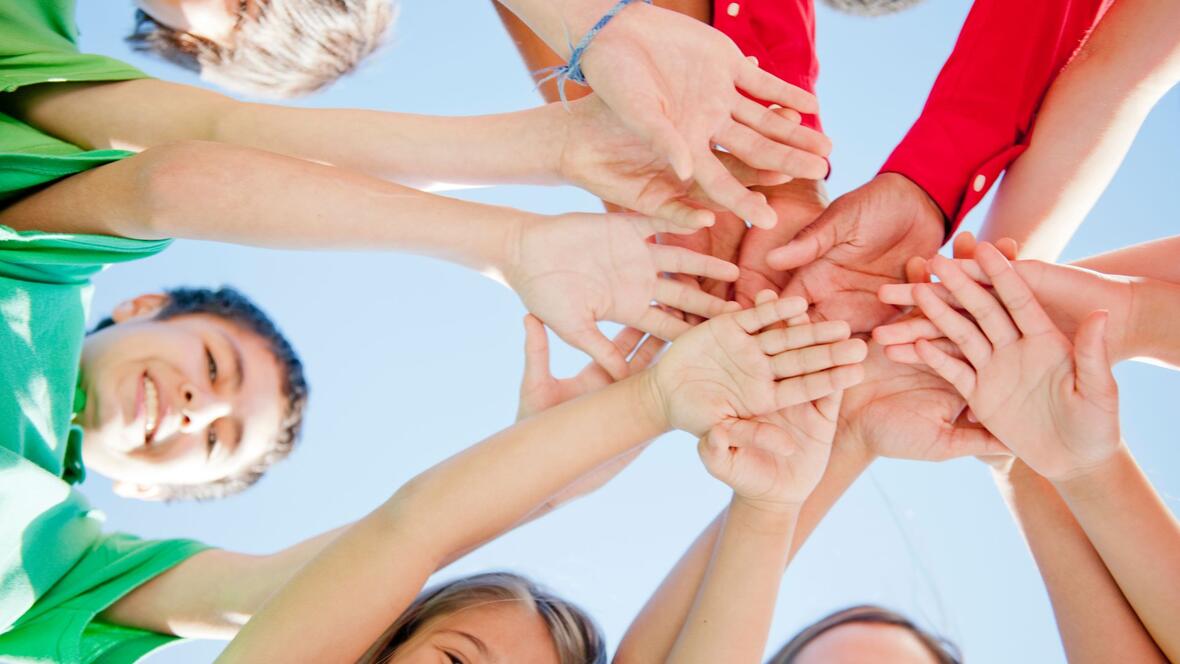 Gruppe von Kindern, die ihre Hände in die Kreismitte ausstrecken